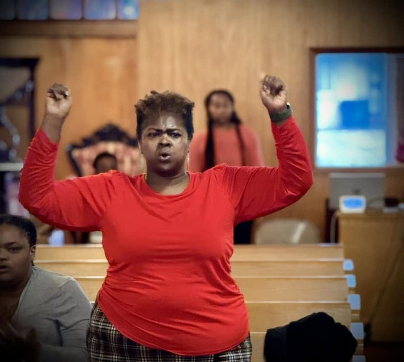 Member worshiping with raised hands at Word of Life Faith Church